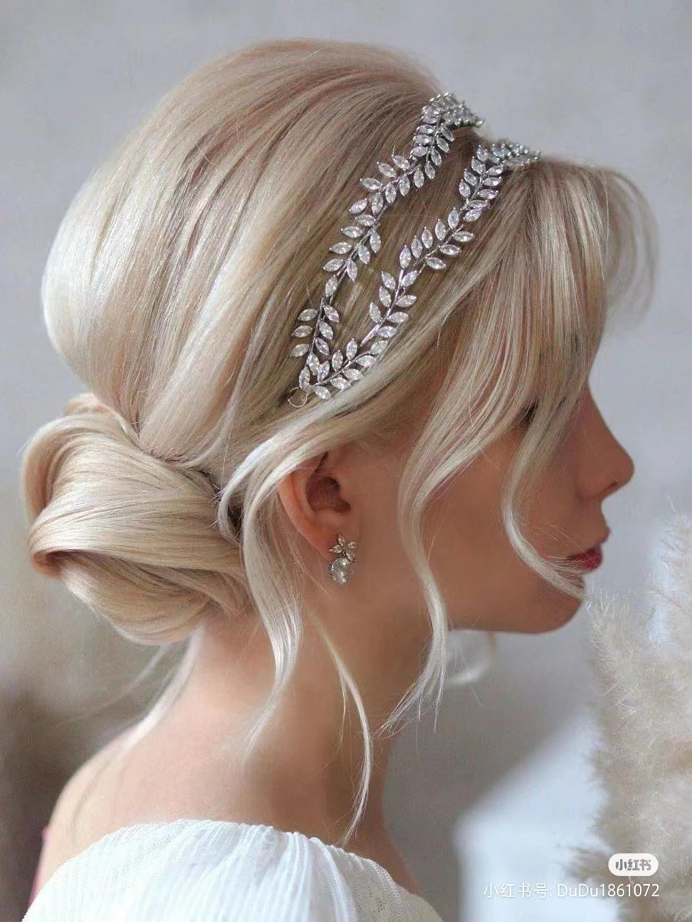 A blonde bride wearing a luxury leaf-inspired cubic zirconia bridal headband.