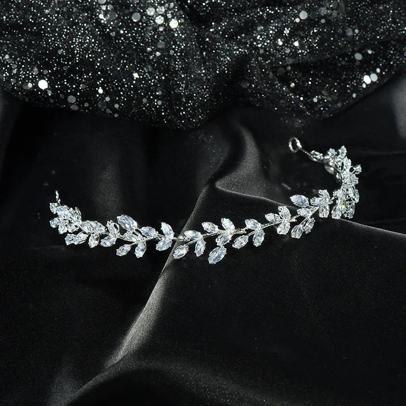 A sparkling bridal headband featuring a refined leaf pattern on a black fabric display.