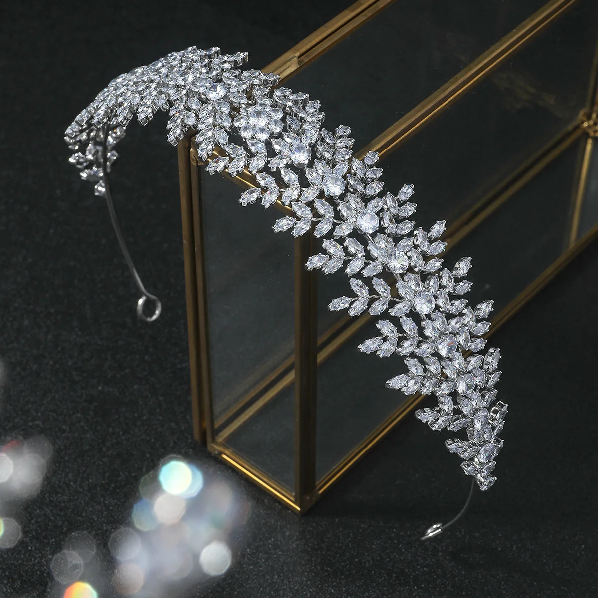 A luxury bridal headband featuring an intricate leaf design crafted with sparkling cubic zirconia crystals, displayed on a glass stand.