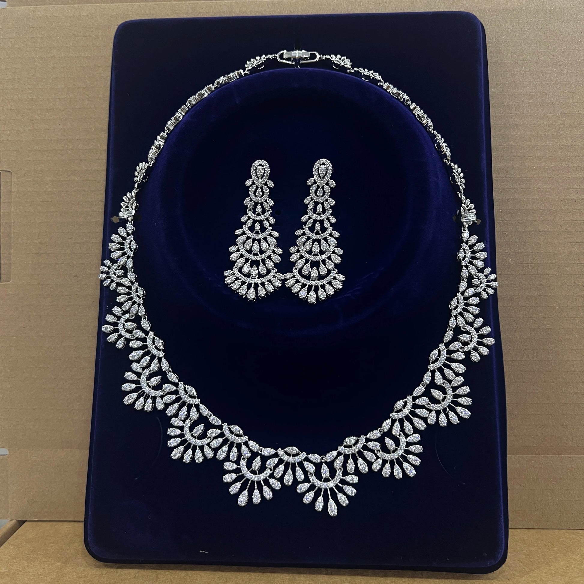 Premium cubic zirconia bridal necklace and matching statement earrings presented in a luxury blue velvet display box.
