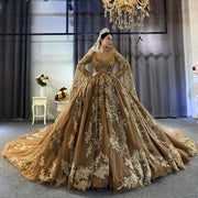 Full front view of a luxury champagne ball gown wedding dress with heavy gold beading, long sleeves, and a matching royal lace veil and tiara