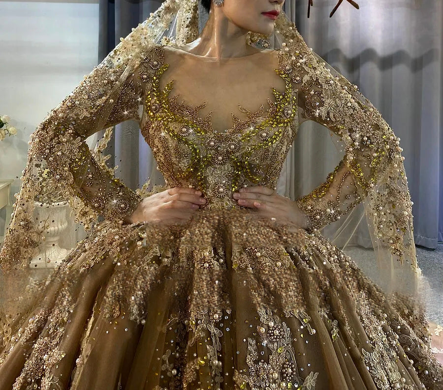 Close-up detail of a champagne bridal gown bodice featuring intricate gold beadwork, crystal embellishments, and a sheer illusion neckline.