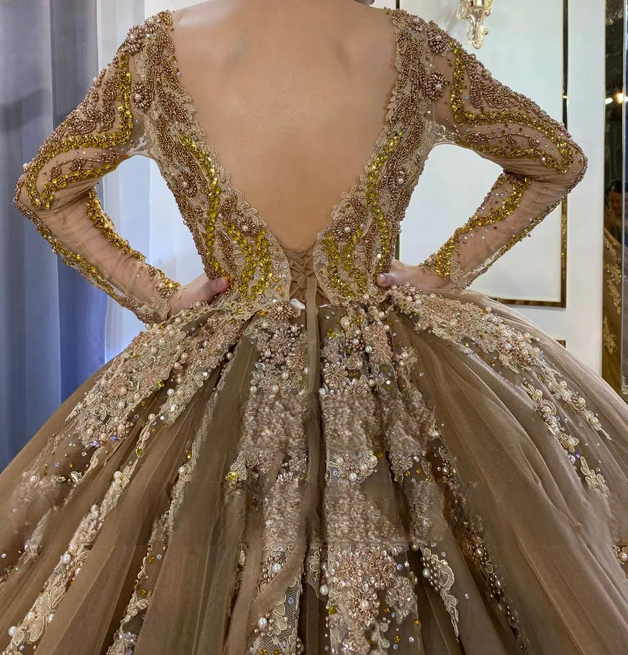 Detailed view of the V-back and waist of a champagne ball gown, featuring heavy gold and pearl beadwork and layered tulle fabric.