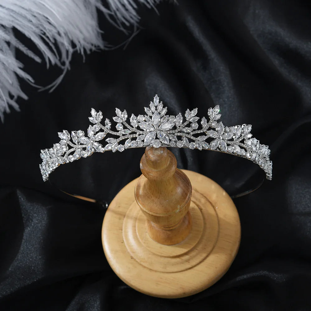 Close-up of a sparkling crystal bridal tiara displayed on a wooden stand.