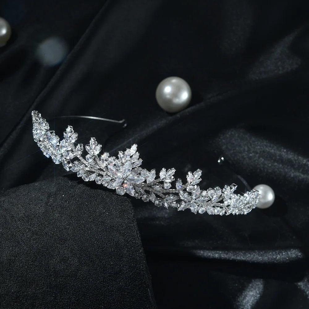 A side-angle view of an elegant silver crystal wedding crown on a display base.