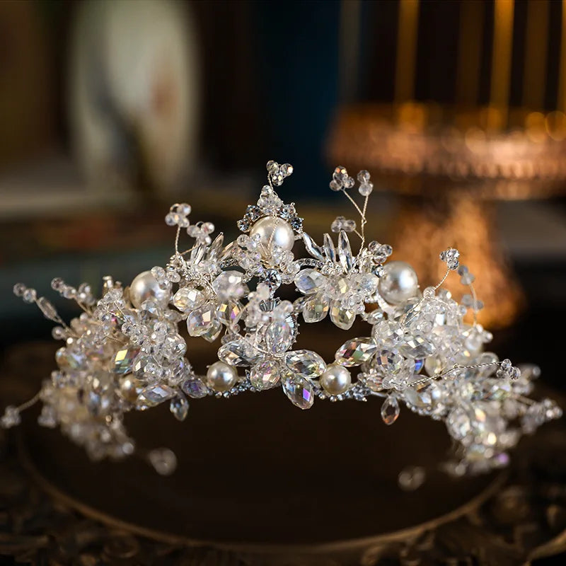 Close-up studio shot of a sparkling luxury crystal pearl bridal crown arranged on a round vintage presentation base.