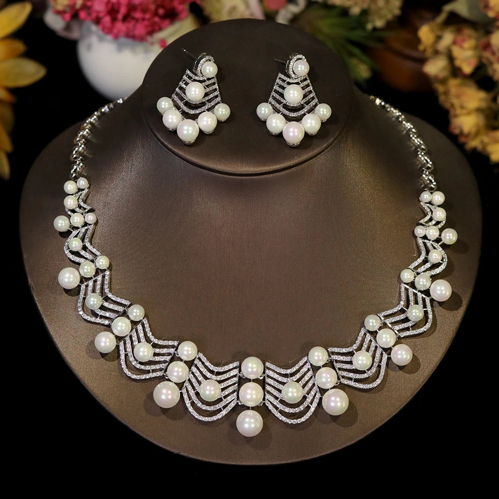 Direct front view of a sparkling cubic zirconia wedding collar necklace and matching pearl earrings on a dark jewelry bust.