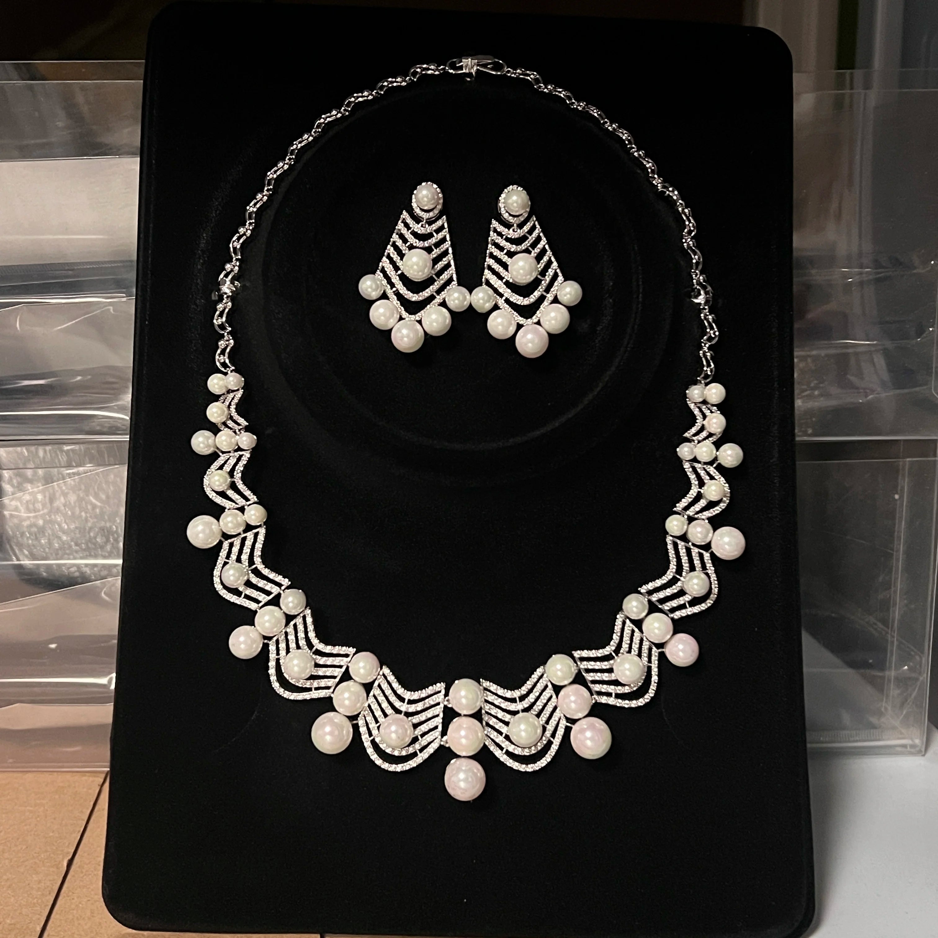 Premium cubic zirconia pearl wedding necklace and statement dropdown earrings presented inside a luxury black velvet display case.
