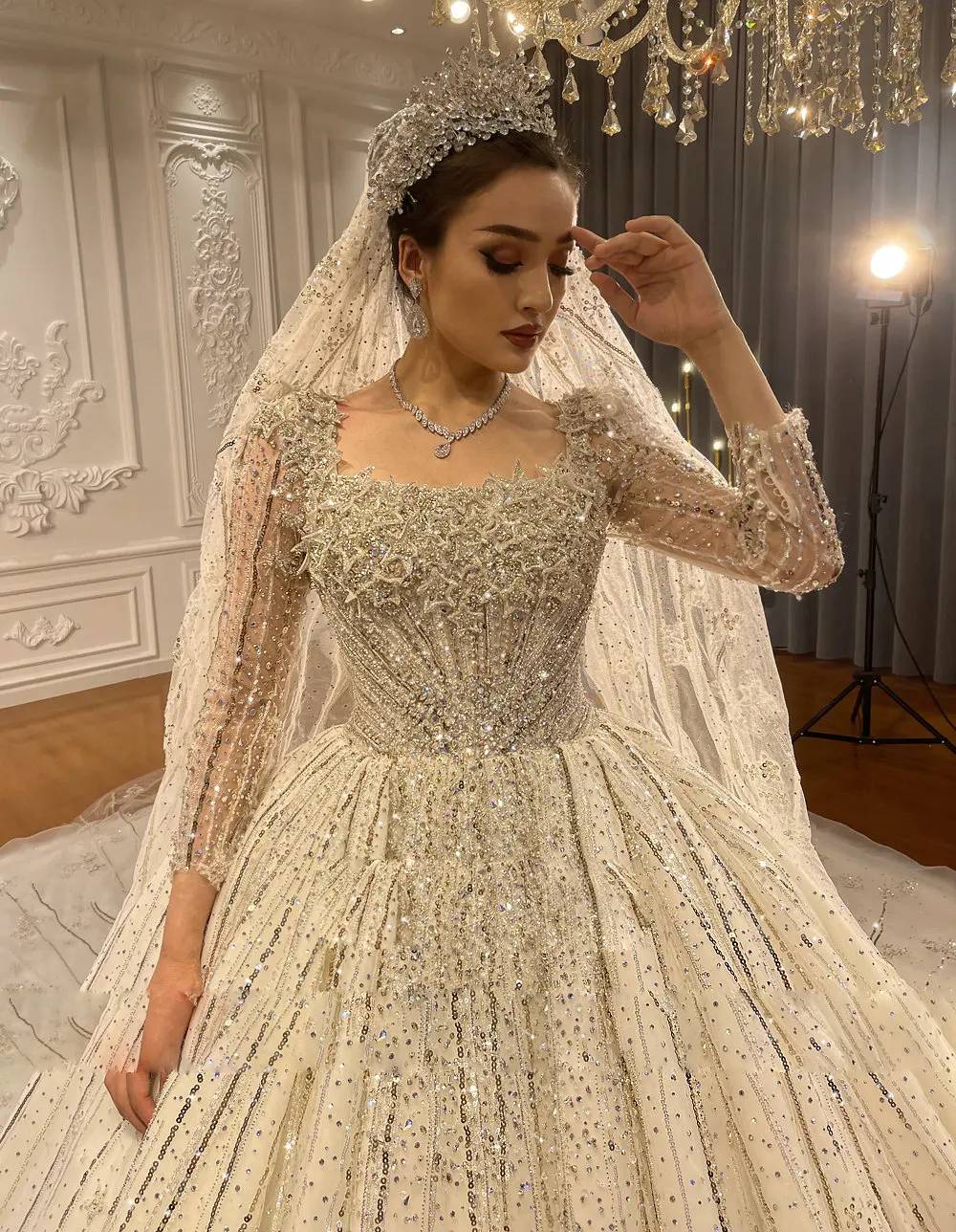 Side profile of a voluminous luxury ball gown wedding dress on a mannequin, emphasizing the grand princess silhouette and reflective silver beadwork patterns.