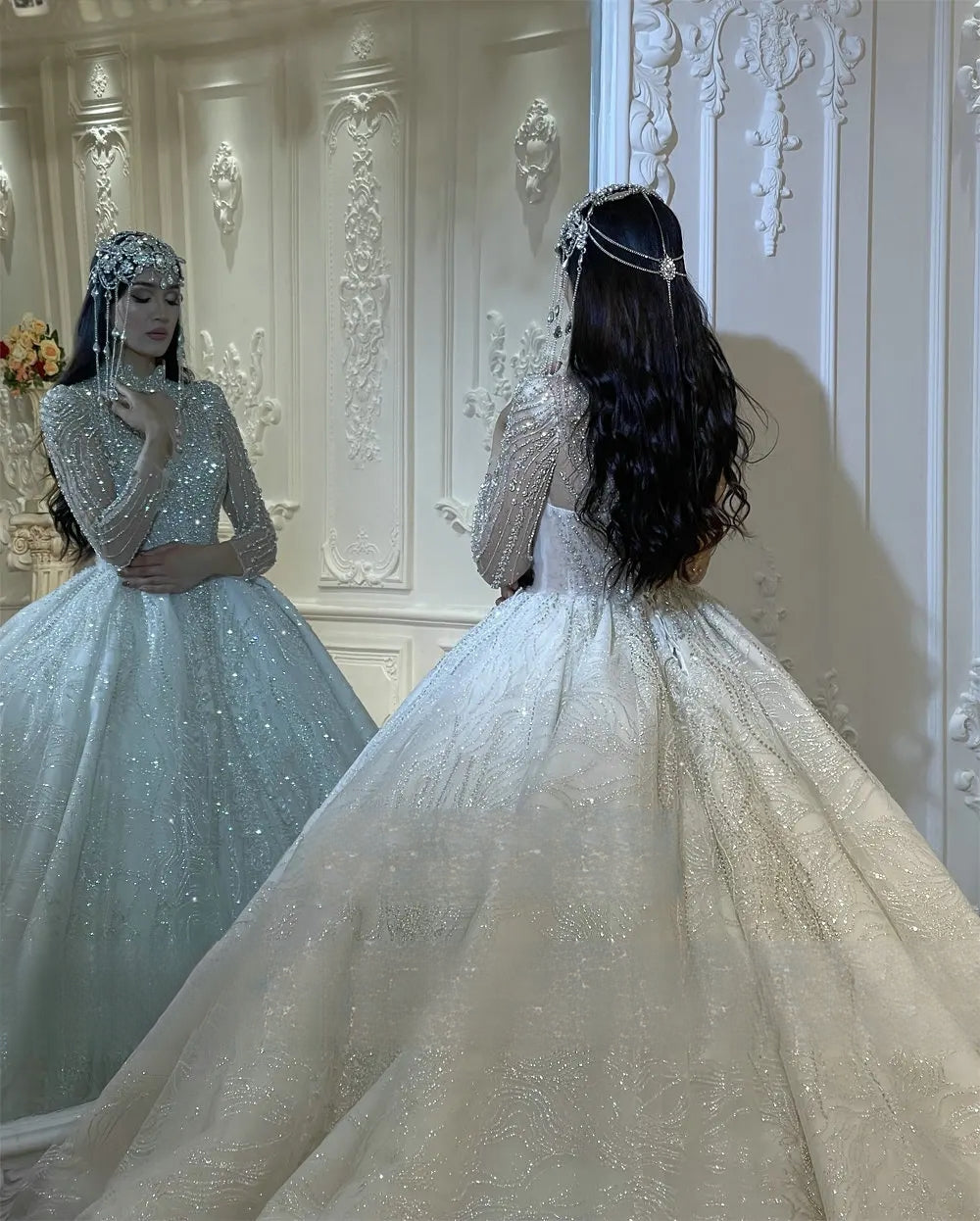 Elegant rear view of a bride looking into a mirror while wearing a luxury heavy-beaded ball gown wedding dress, showcasing the expansive, shimmering train and her reflection revealing the high-neck bodice detail.