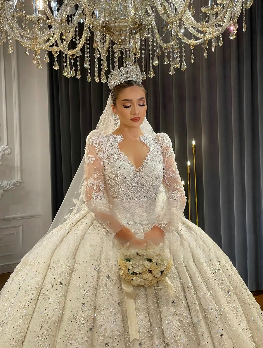 Beautiful close-up of a bride in a luxury Dubai wedding dress with an intricately beaded keyhole neckline, sheer long sleeves, and a sparkling ball gown skirt.
