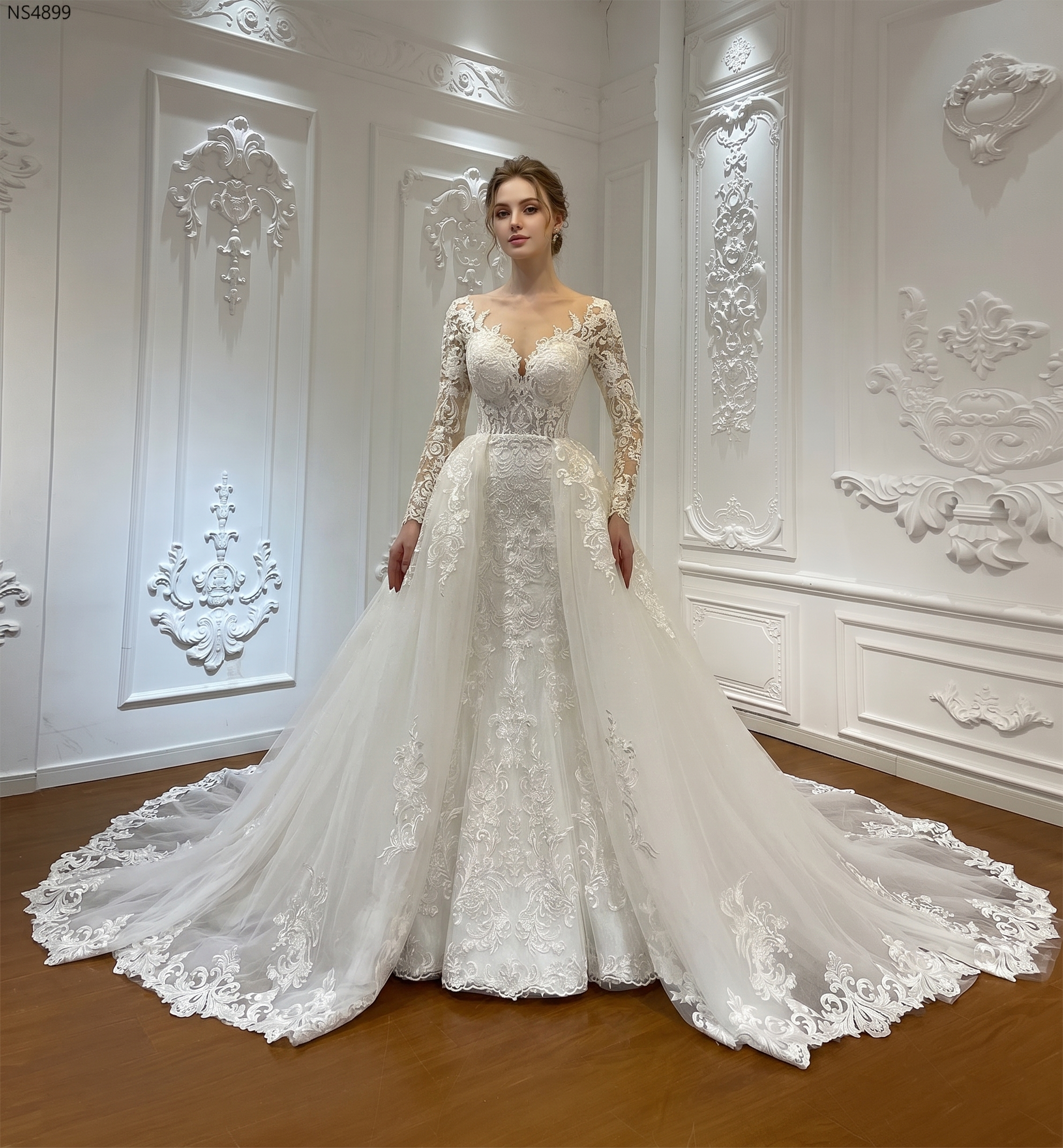 Full front view of a luxury two-piece mermaid wedding dress with a high neck and long sleeves, featuring a grand detachable ball gown overskirt in a bridal showroom.