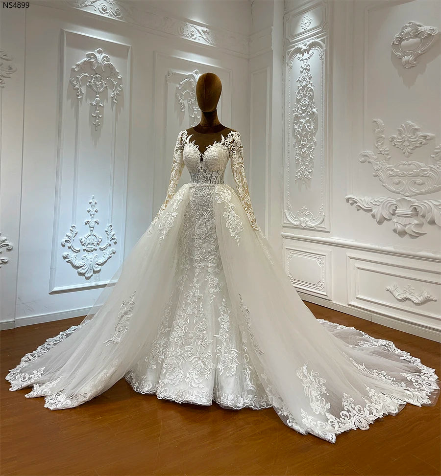 Close-up detail of the waistline on a luxury mermaid wedding dress, showing the seamless attachment of the detachable overskirt and intricate floral lace appliqué.