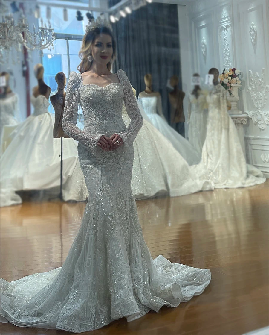 Detailed close-up of the bodice and long sleeves of the luxury full lace wedding dress with complex embellishments and beading, without the overskirt attached.