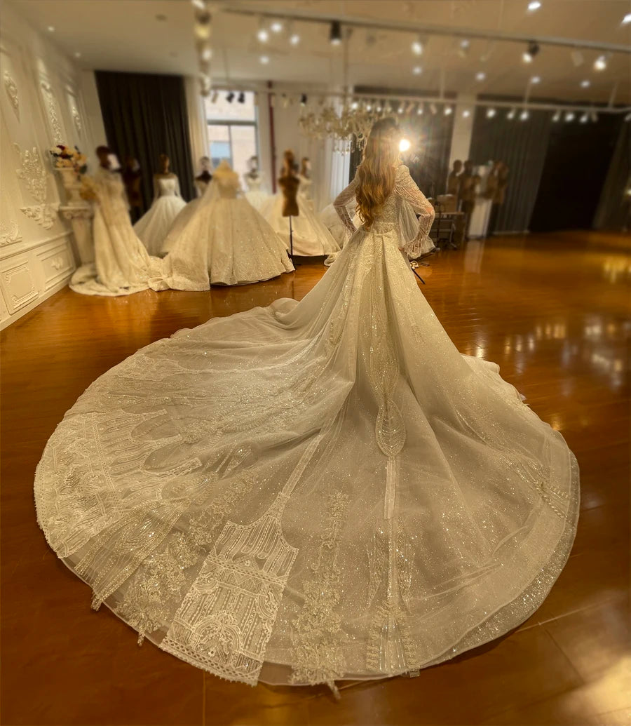 Wide-angle back view of the luxury two-in-one convertible full lace wedding dress, showing the immense length and grand scale of the dramatic, detailed train with the overskirt attached.