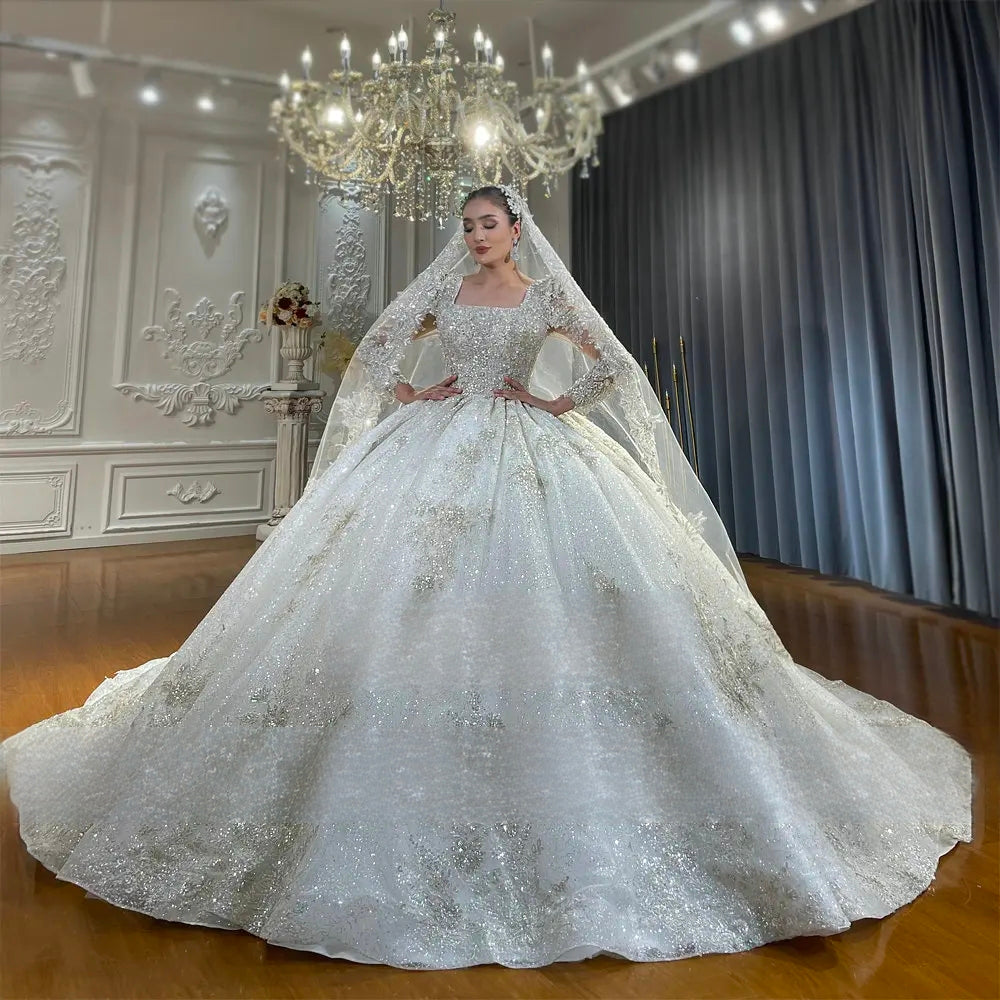 Full front perspective of the luxury handmade ball gown wedding dress, emphasizing the voluminous sparkling skirt, structured square-neck bodice, and regal bridal silhouette.