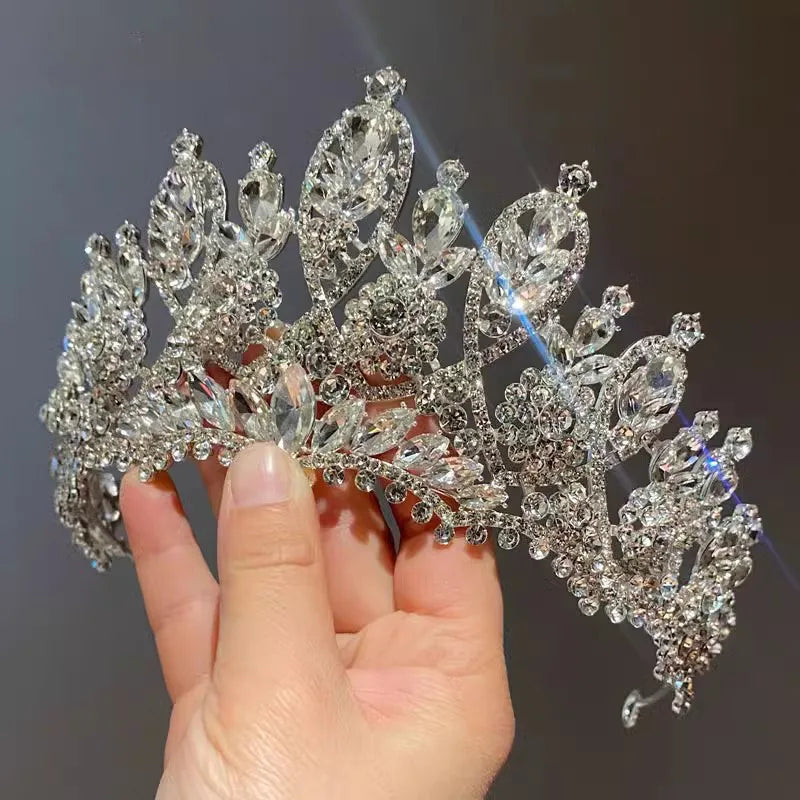 Close-up of a sparkling, luxury handmade bridal tiara being held, showing intricate crystal detailing.