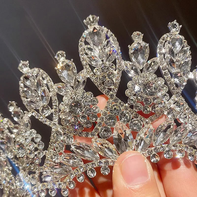 Hand holding a luxury bridal crystal crown, showcasing the craftsmanship and intricate design details.