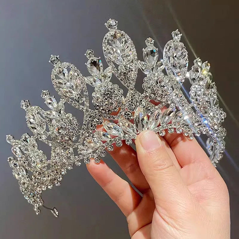 Hand holding a luxury handmade crystal crown, highlighting the sparkling wedding tiara's elegant structure.