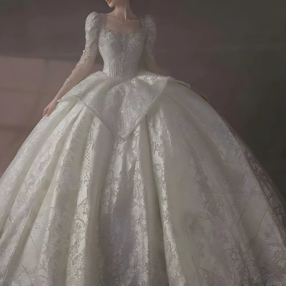 Majestic front pose of a long-sleeved international wedding ball gown with a structured square neckline and a voluminous sparkling skirt.