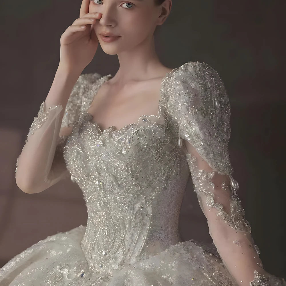 Close-up detail of the backless square collar design on a luxury bridal dress, highlighting the intricate shimmer patterns and sheer long sleeves.