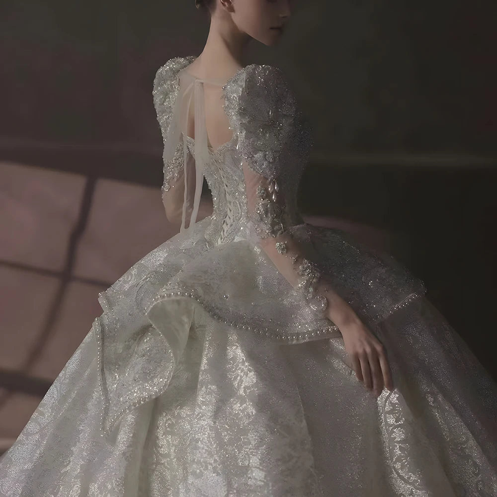 Grand full-length back profile of a shimmering luxury wedding dress, emphasizing the royal princess silhouette and the expansive wide-sweep train.
