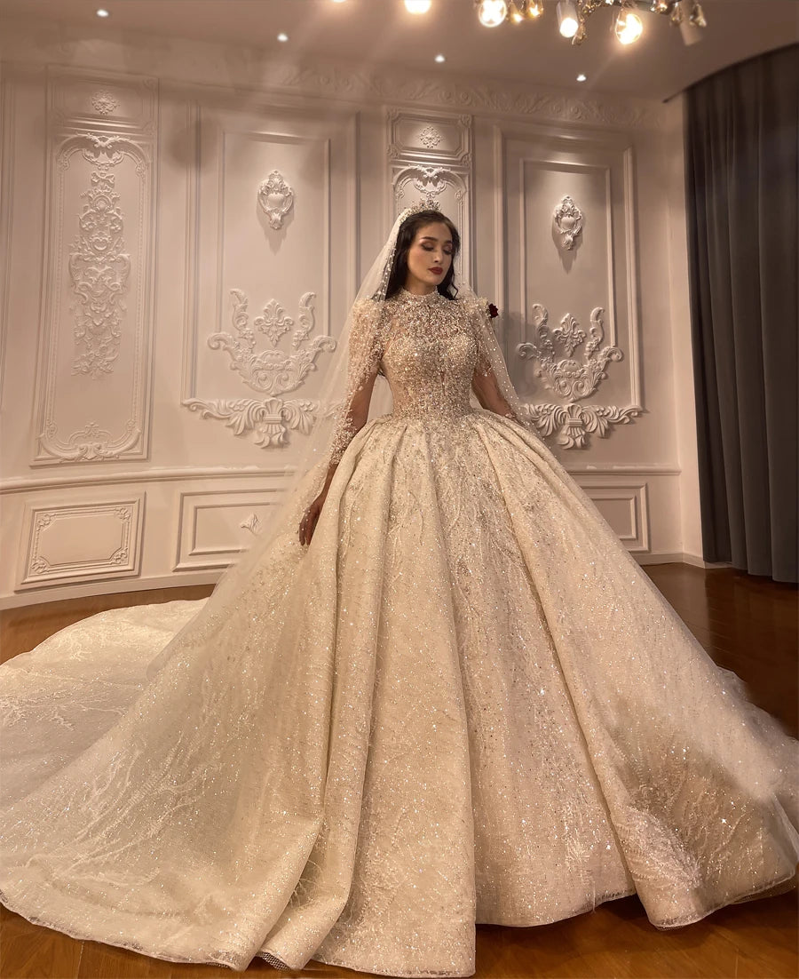 A beautiful bride looking down, showcasing the full volume and heavy crystal detailing of her luxury lace appliqued ball gown wedding dress.