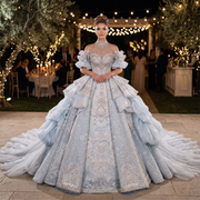 Bride wearing a luxury lace halter ball gown wedding dress with exquisite customized silver embroidery at an outdoor ceremony under a floral arch.