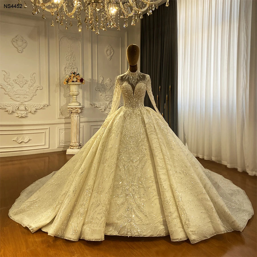 Professional showroom display of a beaded luxury wedding dress on a mannequin, highlighting the classic princess silhouette and uniform sparkling lace patterns from the high collar to the floor-length hem.