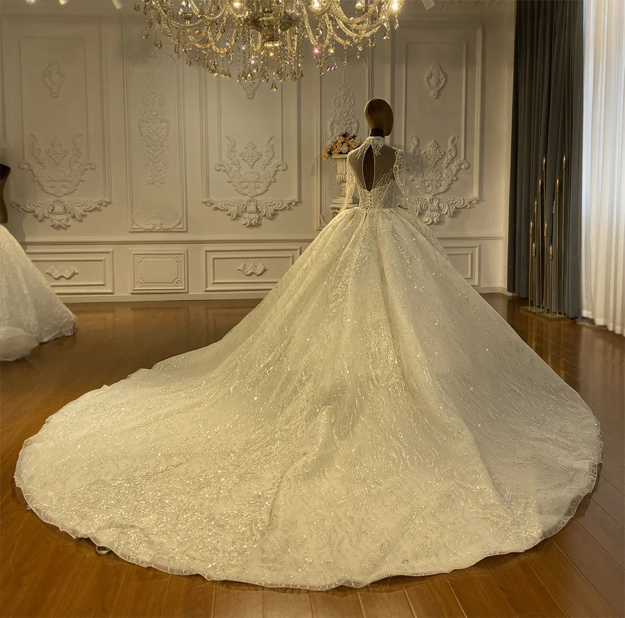 Dramatic rear view of the lace ball gown wedding dress on a mannequin, displaying an elegant keyhole back cutout, corset lace-up closure, and an expansive, glittering cathedral train.