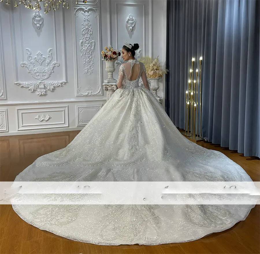 Detailed close-up of a high-neck lace wedding dress bodice, featuring heavy pearl and crystal beading and the delicate sheer lace texture of the elegant long cape.