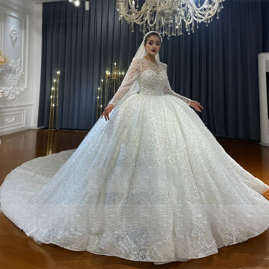 Side angle of a bride posing in a luxury pearl-encrusted wedding gown, emphasizing the grand scale of the sparkling ball gown skirt.