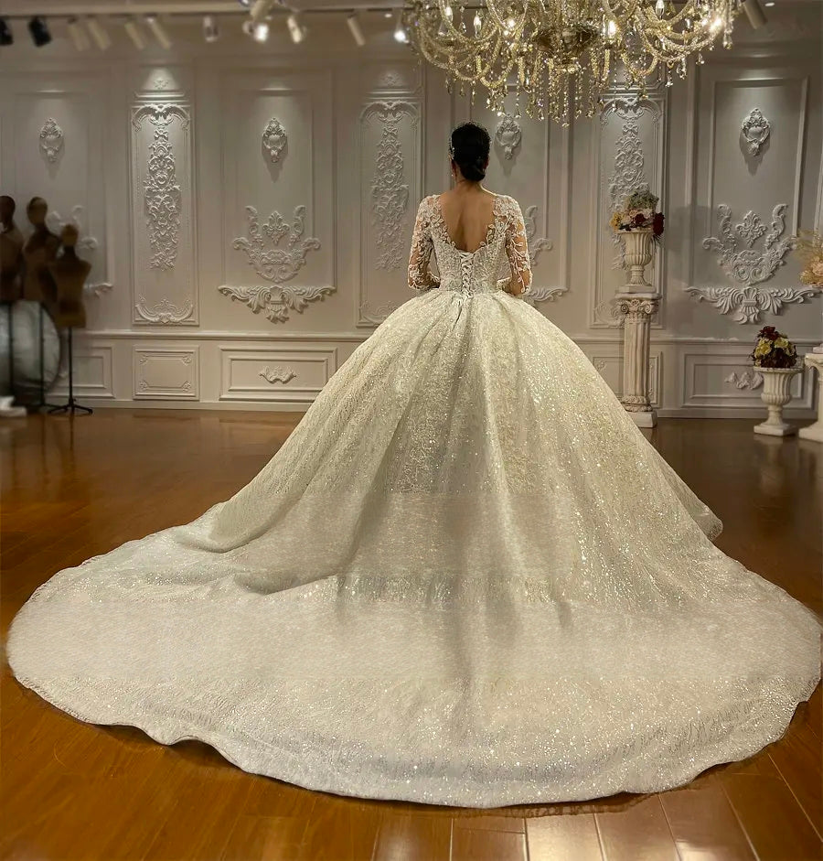 Rear perspective of a luxury ball gown wedding dress featuring a sophisticated V-shaped back with a lace-up corset and a majestic, sweeping cathedral-length train.