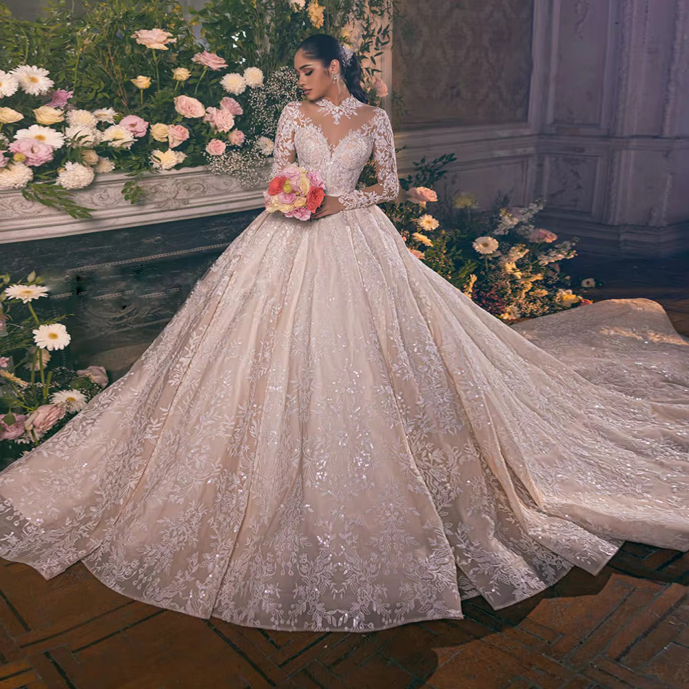 Luxury long sleeve ball gown wedding dress with a modest jewel O-neckline, intricate frosted lace appliques on a sheer bodice, and a voluminous layered tulle skirt.