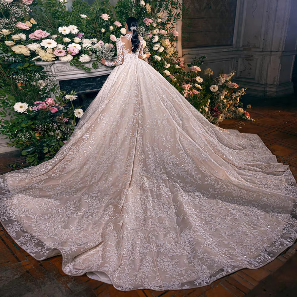 Rear view of a luxury princess bridal ball gown showcasing a sheer illusion lace back with button closures and an expansive cathedral-length trailing tulle skirt.