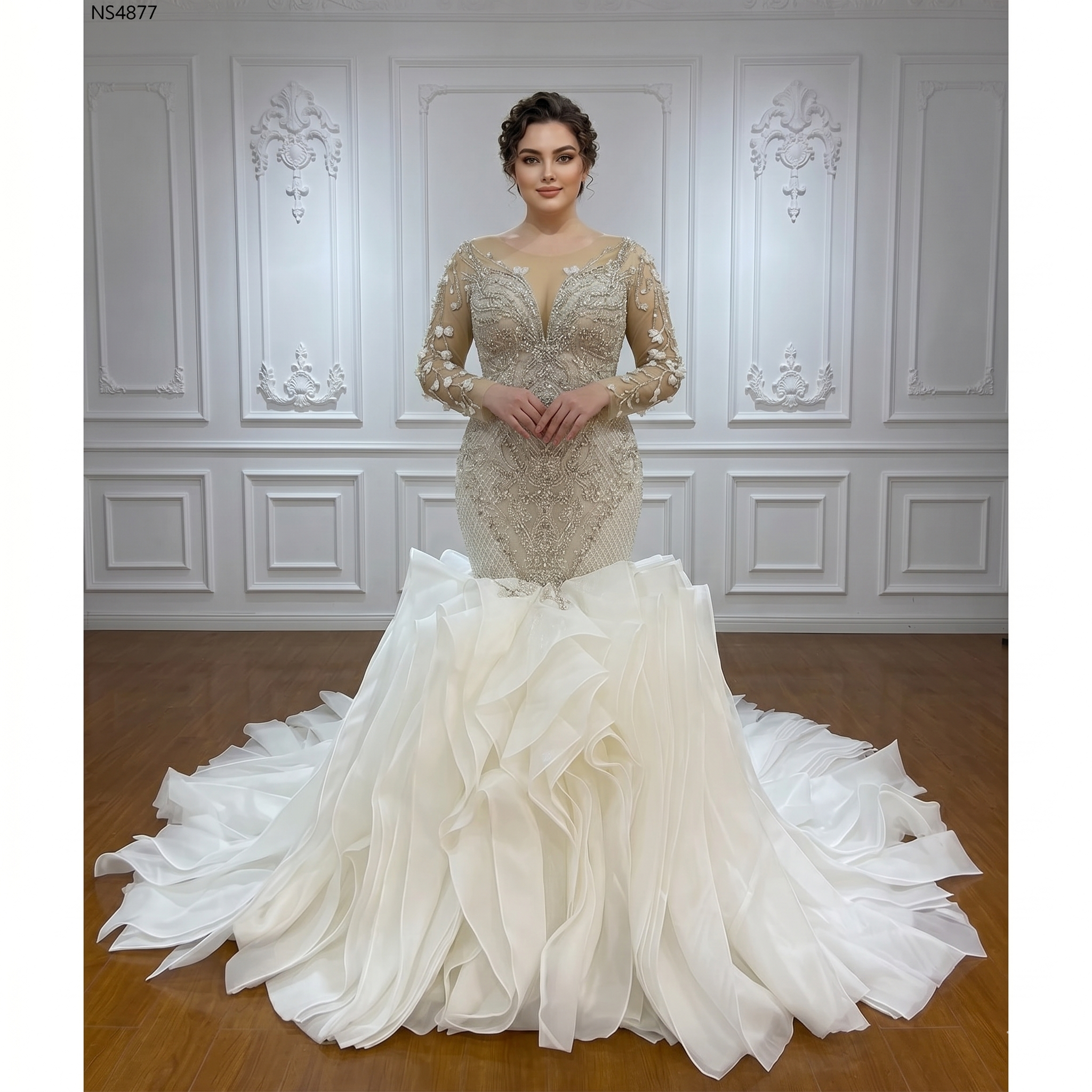 A bride wearing a beaded long-sleeved mermaid wedding gown featuring a voluminous, tiered ruffled skirt and elegant detailing.