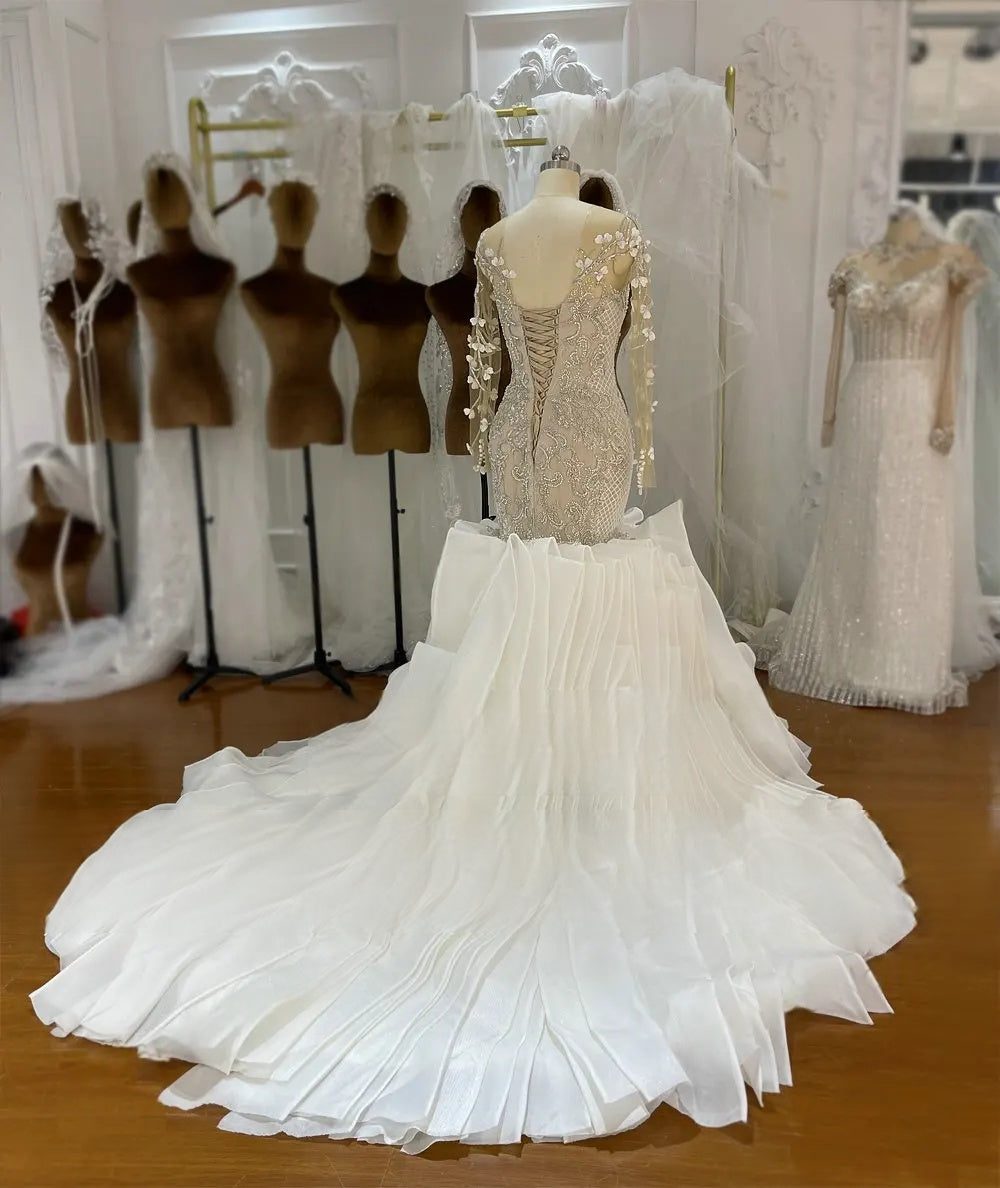 Back view of a mermaid wedding gown on a mannequin, highlighting a sophisticated lace-up corset back and an expansive ruffled train.