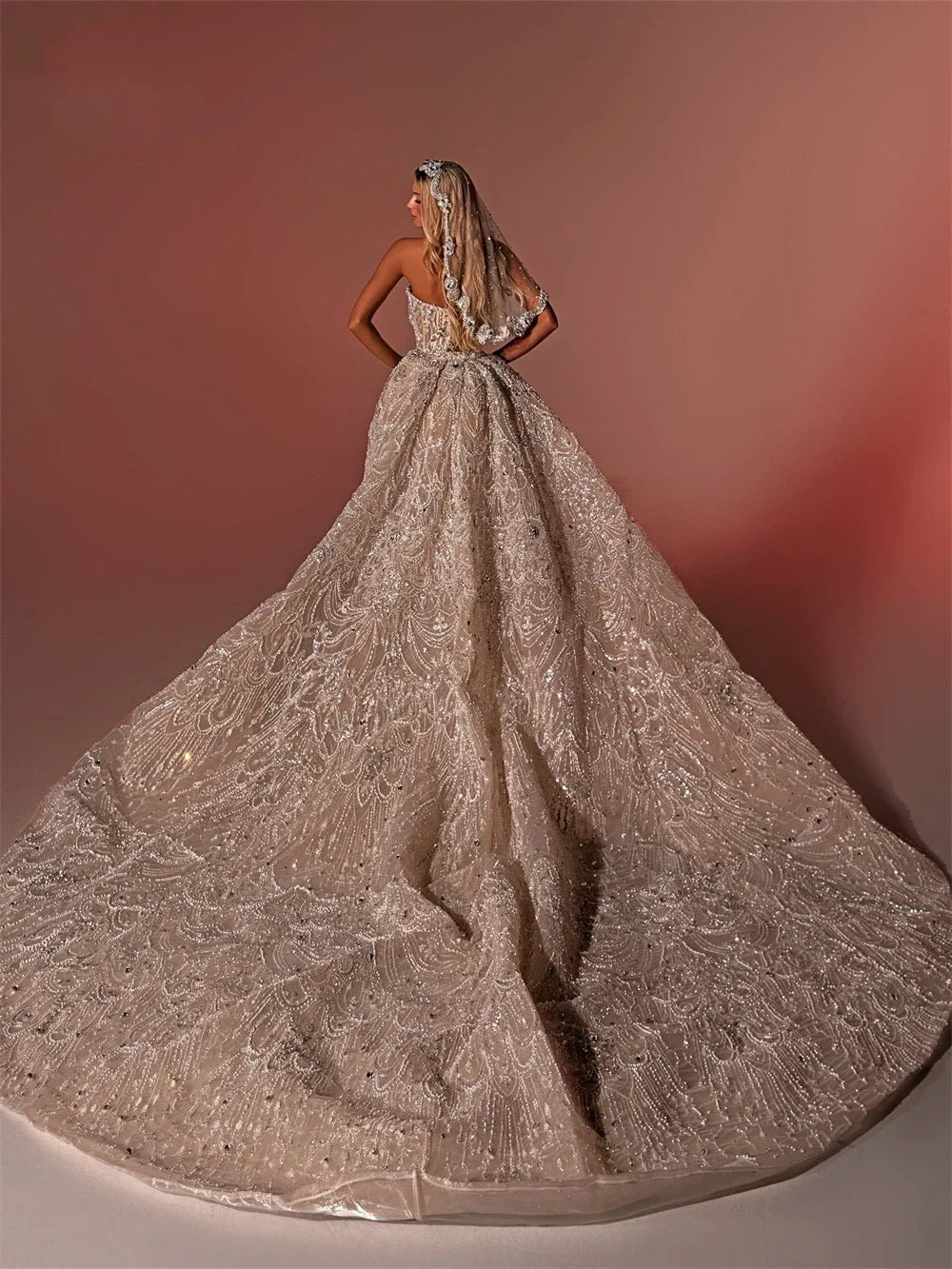 Rear view of a luxury heavily beaded wedding dress showing the sprawling grandeur of a custom shimmering detachable cathedral overskirt train.