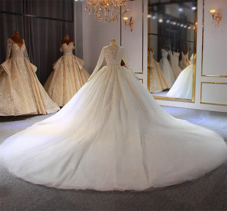 Wide back view of a luxury white Muslim wedding dress, illustrating the grand scale of the sparkling cathedral train on a modest full-cover bridal gown.
