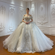 Elegant off-shoulder luxury French lace bridal gown featuring romantic long sleeves and a flowing A-line silhouette.