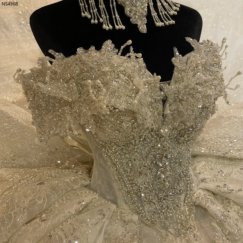 Front view of a luxury French lace designer bridal gown showcasing elegant long sleeves and intricate floral beadwork.