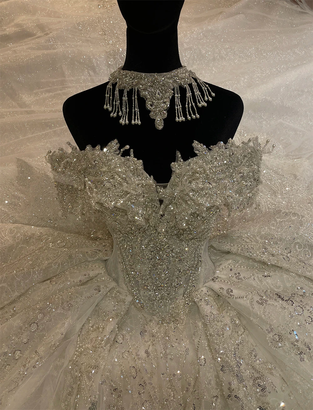 Full rear view of a luxury lace bridal gown highlighting an expansive shimmering train with delicate scalloped edges.