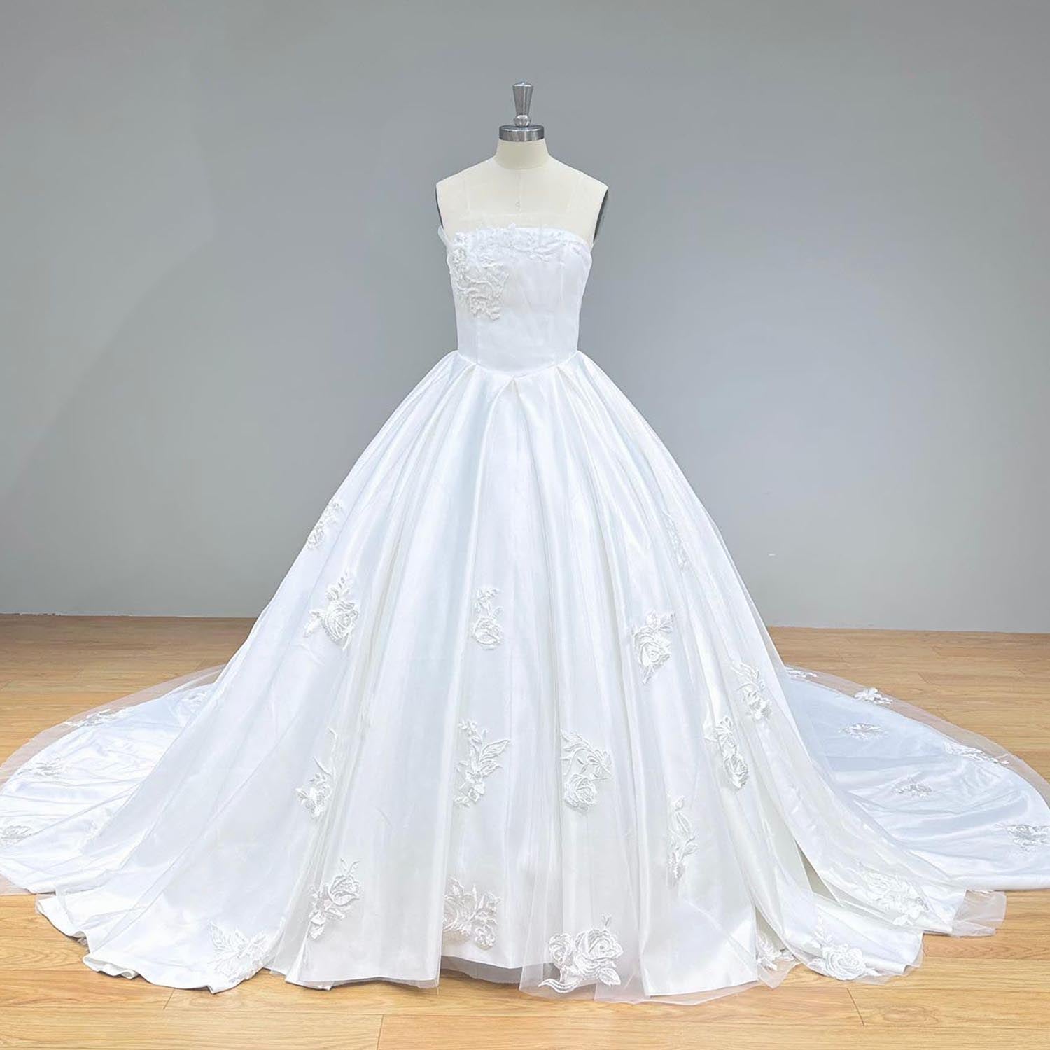 Classic full front studio view of a luxury off-shoulder boat neck ball gown wedding dress on a mannequin, capturing the voluminous pleated satin skirt and intricate floral lace detailing.
