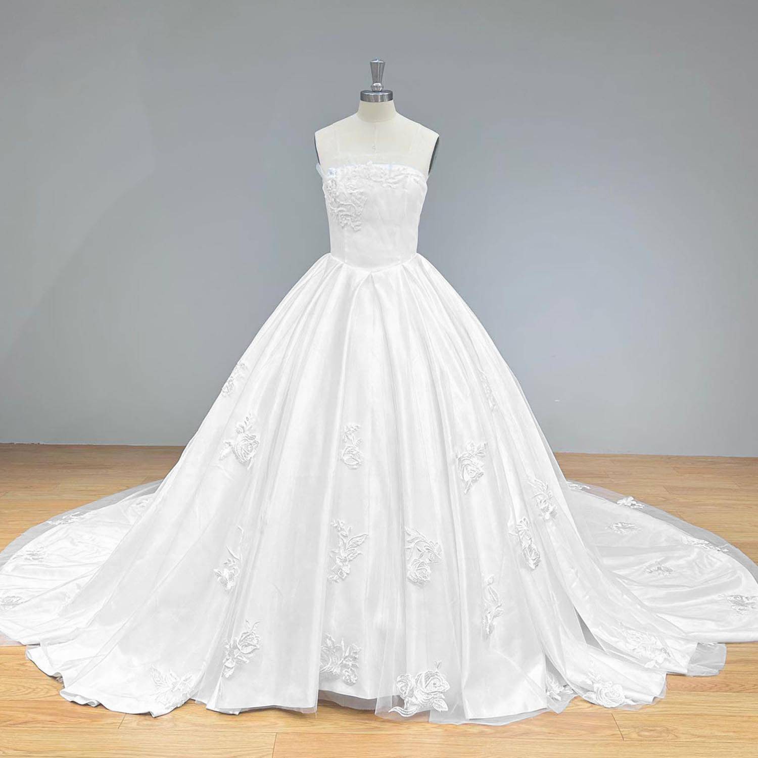 Wide front view of an elegant luxury ball gown wedding dress on a mannequin, perfectly showcasing the wide sweeping satin skirt, delicate scattered floral appliques, and timeless bridal silhouette.