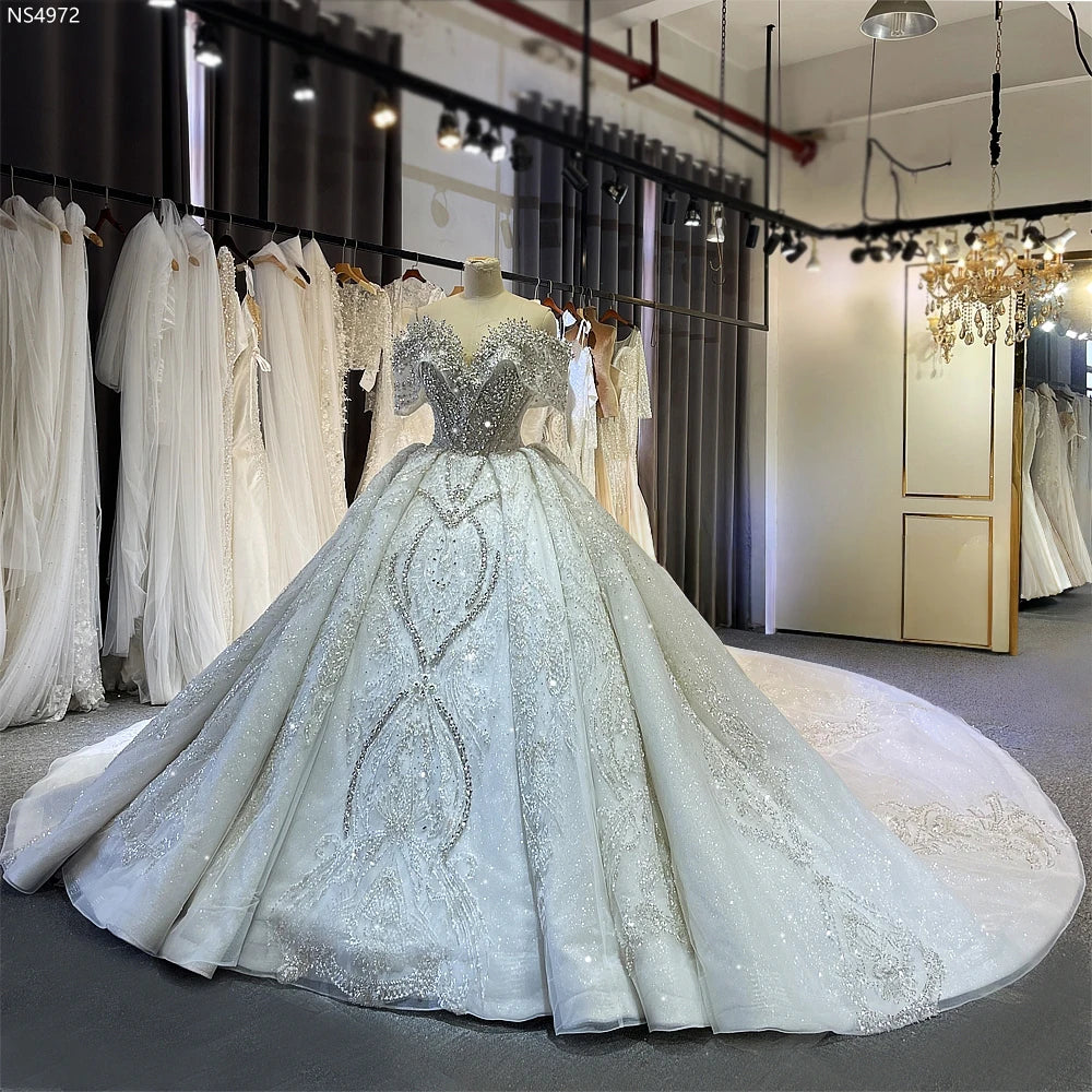 Front view of the luxury off-the-shoulder beaded ball gown wedding dress on a mannequin, highlighting the heavy crystal embellishments and elegant silhouette.
