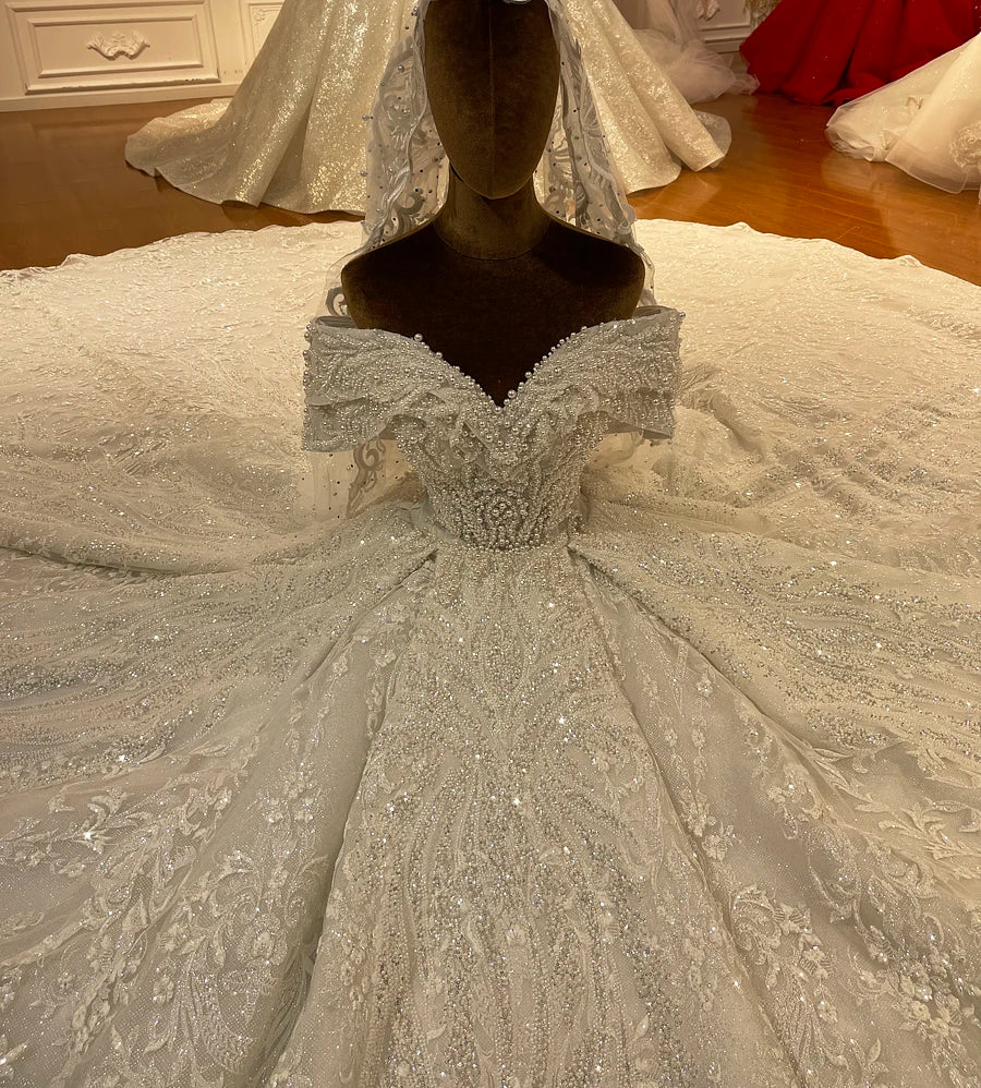 Close-up detail of a bridal dress bodice highlighting premium pearl embellishments, a sweetheart neckline, and floral lace textures.
