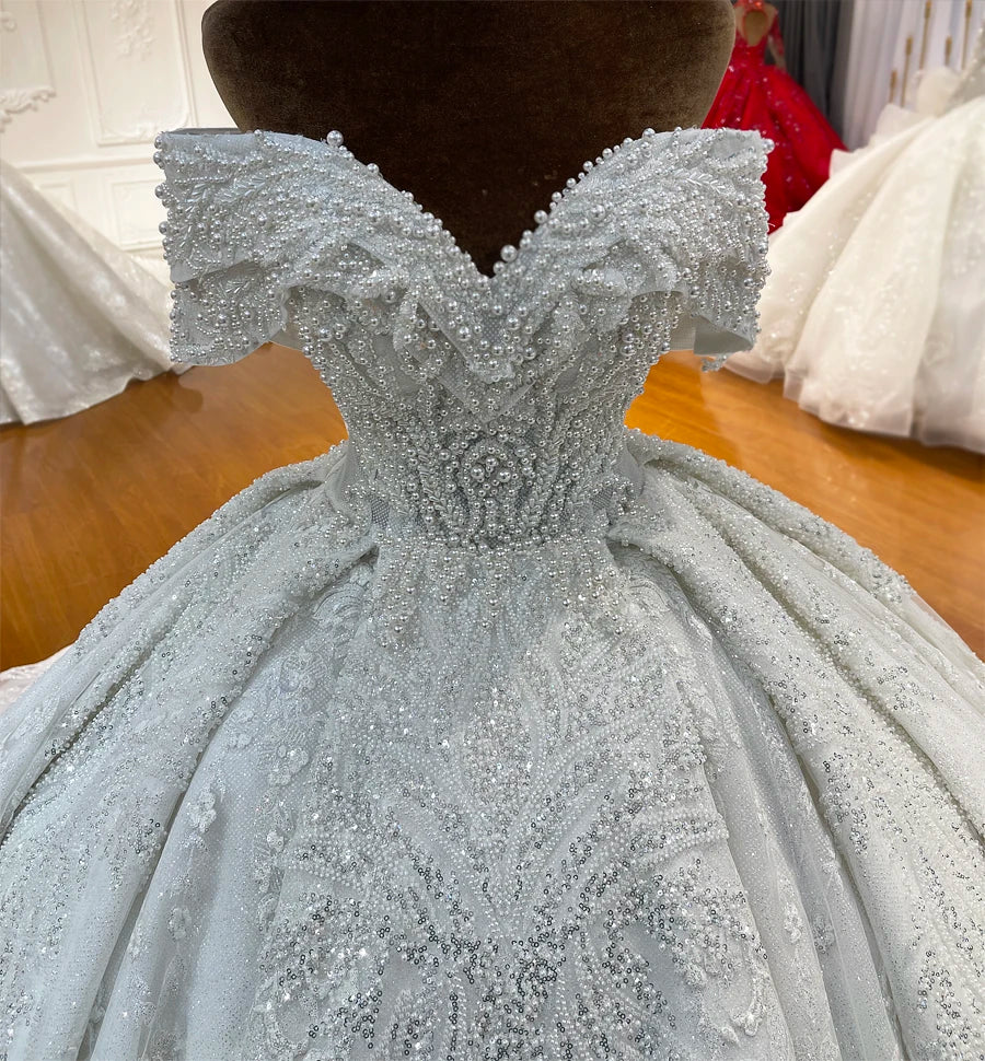 Rear view of a luxury wedding gown featuring a traditional lace-up corset back and a structured, pearl-adorned waistline.