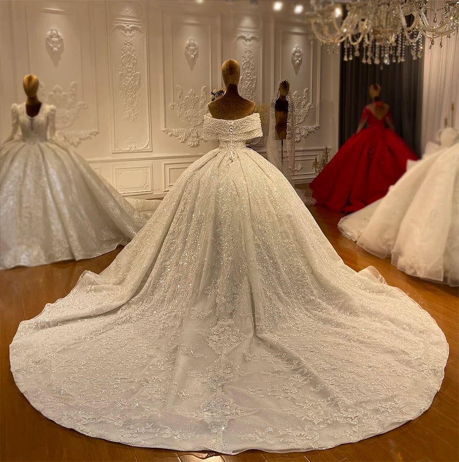 Wide-angle rear view of a shimmering pearl-embellished bridal gown highlighting the full extension of its ornate lace train.