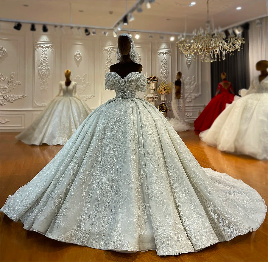 Detailed shot of a luxury bridal train featuring heavy pearl embroidery, shimmering sequins, and intricate scalloped lace.