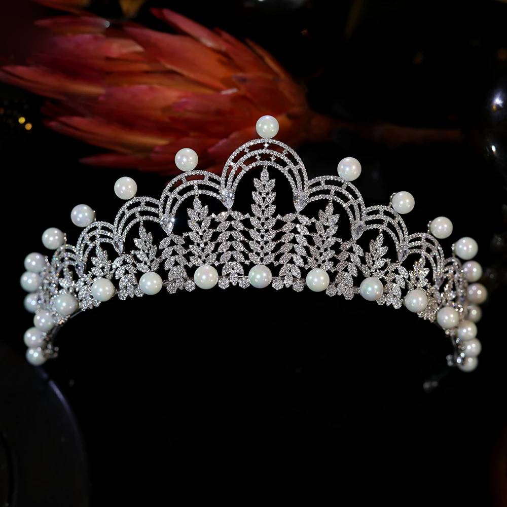 Front view of a luxury pearl wedding crown featuring arched scrollwork and brilliant clear cubic zirconia stones against a dark background.